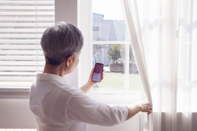 햇살이 들어오는 창가에서 미세먼지 앱을 들여다 보고 있는 노인